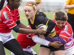 Alyssa Baker of Tillsonburg Glendale High School is tackled by John Paul II players Grace Nnamdi, Kim Kome, and Lena Cripps during their rugby game at the City Wide field in London on Wednesday May 4, 2022. Mike Hensen/The London Free Press