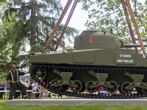 Workers from Modern Crane help ease the suspended 30-ton bulk of the Holy Roller Sherman tank onto its final resting place on a new concrete pad in Victoria Park in London Tuesday, May 31, 2022. (Mike Hensen/The London Free Press)