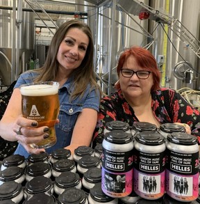 London graphic artist Darla Stratton, left, holds a glass of Anderson Craft Ales’ Helles beer with Forest City London Music Hall of Fame curator Rena O’Halloran leaning on a stack of beercans, designed by Stratton, bearing the images of several inductees to the hall of fame.  (JOE BELANGER/The London Free Press)