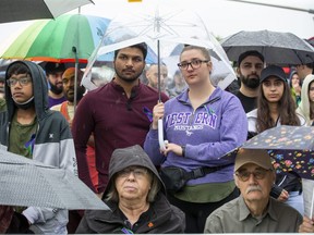 Two people stand under an umbrella as the rain falls at a vigil Monday, June 6, 2022, for members of the Afzaal family. A new memorial to the family was unveiled at the event marking the one-year anniversary of their deaths in what police allege was a hate-motivated attack. (Derek Ruttan/The London Free Press)