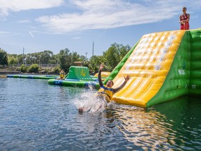Lifeguard Jarod Medd keeps an eye on St. Marys Mayor Al Strathdee as he enjoys the new inflatable waterpark opening at the St. Marys Quarry. St. Marys events co-ordinator Andrea Macko is capturing the moment. (Chris Montanini/Postmedia Network)