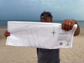 An Ipperwash Beach lakefront cottage owner named Wayne who didn’t want his last name published out of fear of retribution holds up a deed showing his property lines extend to the edge of Lake Huron. Terry Bridge/Sarnia Observer