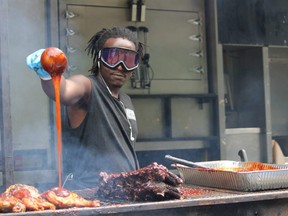 Cook Chimba Musafirii of Oak & Barrell barbecue pit kept the line-up for ribs and chicken entertained with his dramatic moves with sauces and fire at the opening Thursday of the five-day London Ribfest and Craft Beer Festival. (JOE BELANGER/The London Free Press)