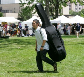 Toronto's Brian Kobayakawa, who plays with the Creeking Tree String Quartet, carries a double bass on his back as he heads to a stage in Victoria Park for a workshop during the festival in 2007. (London Free Press file photo )