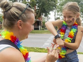 Stephanie Yost and her daughter Charlotte, 7, wait for the Pride Parade playing Cat's Cradle on Waterloo and Dufferin in London.