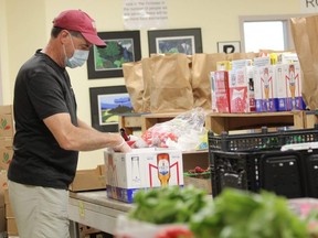 London Food Bank volunteer Jeff Moores fills a box with fresh produce at the organization's Leathorne Street headquarters. (Free Press file photo)