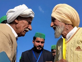 This handout picture taken on Jan. 12, 2022 and received as a courtesy of Pakistan's Youtuber Nasir Dhillon shows Indian Sikh labourer Sika Khan, right, speaking with his elder brother Sadiq Khan from Pakistan near the India-Pakistan border at the Kartarpur corridor. Tears of joy rolled down his wizened cheeks when Indian Sika Khan met his Pakistani brother for the first time since being separated by Partition in 1947. Sika was just six months old when he and his elder brother Sadiq Khan were torn apart as Britain split the subcontinent at the end of colonial rule. (Photo by Courtesy of Nasir Dhillon / AFP)