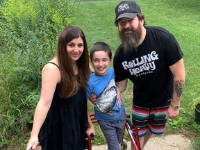 The stairs to the front door of his Brantford home are just one of the barriers facing 10-year-old Brodie Watson, flanked by his parents, Michelle and Mark Watson. Brodie's family has created a fundraiser in hopes of helping to create an accessible home for him. (SUSAN GAMBLE/Postmedia Network)