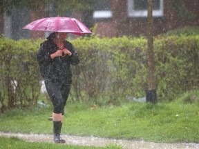 Shannon Pakulis of London manages to keep smiling as she gets totally drenched even with an umbrella in the downpours and hail as she walks along Central Ave. in this file photo.