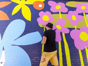 Artist Andrew Lewis works on a 90-by-14-foot mural wrapping around the south and east walls of the new Libro Credit Union at 578 Richmond St. on Richmond Row in downtown London
Photograph taken on Friday August 12, 2022. (Mike Hensen/The London Free Press)