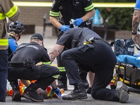 Windsor police and EMS paramedics treat a man suffering from a gunshot wound after he was shot by police while threatening people with a machete on Wyandotte Street West at Ouellette Avenue, on Monday, Aug. 15, 2022.  (DAX MELMER/Windsor Star)
