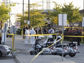 Police vehicles and officers are seen behind tape at a scene in Mississauga on  Monday, Sept. 12, 2022. A Toronto police officer has been fatally shot and a suspect is dead after shooting scenes spanning three Greater Toronto Area cities Monday afternoon, left a third person dead and three others injured. THE CANADIAN PRESS/Arlyn McAdorey