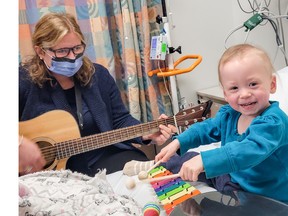 Baby Kayleigh breaks out in a wide grin while playing the xylophone while music therapist Karina strums on the guitar. Supplied