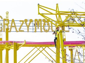 Alphonso Lorenzo Garcia of North American Midway Entertainment works six metres above the ground while erecting the Crazy Mouse roller-coaster at Western Fair in London on Thursday, Sept. 8, 2022. The fair opens Friday afternoon. (Derek Ruttan/The London Free Press)