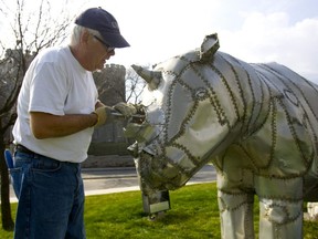 London artist Tom Benner repairs damaged aluminum on his beloved white rhino sculpture outside Museum London in 2012. Benner, who gained wide acclaim during his four-decade art career, has died. (MIKE HENSEN/The London Free Press)