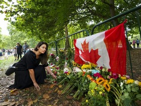 Canadian Kersten Samolczyk who now resides in the United Kingdom places flowers by a Canadian flag as thousands of mourners lay flowers as people pay their respects near the gates of Buckingham Palace in London on Sunday, September 11, 2022. Queen Elizabeth II, Britain's longest-reigning monarch and a rock of stability across much of a turbulent century, died Thursday Sept. 8, 2022, after 70 years on the throne. She was 96.