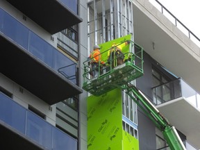 Edgar Quesda and Cesar Escobar of Titan Construction attach a form of drywall before the cladding is installed at York Developments ParkVu tower at the corner of Wonderland Road and Springbank Drive in London on Oct. 7, 2022. (Mike Hensen/The London Free Press)