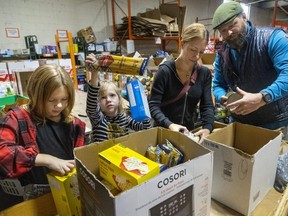Charlie Barnett, 9, and sister Zoe Barnett, 7, sort through donated food at the London Food Bank as they volunteer with parents Jen and Patrick Barnett. Photograph taken on Monday October 10, 2022.  (Mike Hensen/The London Free Press)