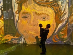 Yi Chen holds his seven-year-old son Isaac in front of a massive projection of a Vincent Van Gogh painting at the Imagine Van Gogh immersive exhibit that opened this weekend at 100 Kellogg Lane in London. Mike Hensen/The London Free Press