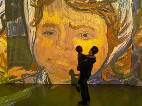 Yi Chen holds his seven-year-old son Isaac in front of a massive projection of a Vincent Van Gogh painting at the Imagine Van Gogh immersive exhibit at 100 Kellogg Lane in London. (Mike Hensen/The London Free Press)