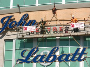 Construction workers attach the John Labatt Centre sign to the outside of the new downtown arena on Oct. 10, 2002. (Free Press file photo)