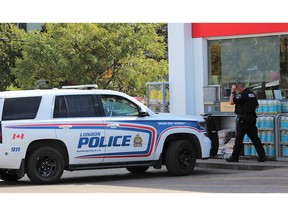 A London police officer leaves a gas station at the corner of Oxford Street and Hyde Park Road on Tuesday. Officers canvassed homes and businesses in the area as part of an investigation into a hit-and-run crash that seriously injured two pedestrians on Monday night. (DALE CARRUTHERS/The London Free Press)