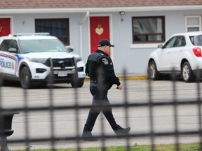 A London police officer walks through the parking lot of the American Plaza Motel on Dundas Street as police probe a possible shooting that left a man hurt Friday, Nov. 25. (Dale Carruthers/The London Free Press)