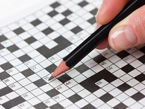 female hand holding a pencil and solves crossword puzzle