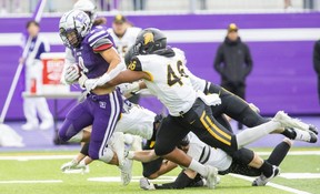 Four Waterloo Warriors beat the Western Mustangs against running back Edouard Wanadi in their match at the Western Alumni Stadium in London on Saturday September 24, 2022. The Mustangs won with a score of 66-3.  (Derek Ruttan/The London Free Press)