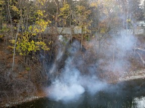London firefighters spray water on hot spots left after a brush fire on the bank of the Thames River near Richmond and Grey streets in London at 5 p.m. on Thursday, Nov. 10, 2022. (Derek Ruttan/The London Free Press)
