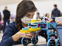 Olivia Flores 14, of St. Mary's Catholic High School in Woodstock studies the robot her team had made as part of the Oxford Invitational Youth Robotics Challenge in Woodstock on Tuesday November 15, 2022. 14 high schools participated.  (Mike Hensen/The London Free Press)