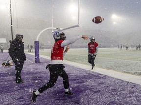 Western Mustangs quarterback Evan Hillock throws in a snow squall at practice under the watchful eye of offensive co-ordinator Gaetan Richard as teammate Jackson White watches at Alumni Stadium in London on Nov. 17, 2022. (Mike Hensen/The London Free Press)