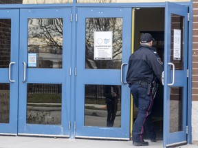 A London police officer stands in the doorway of H.B. Beal secondary school a after stabbing in its cafeteria on Monday Nov. 21, 2022. (Mike Hensen/The London Free Press)