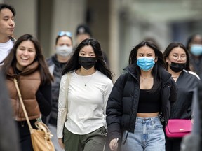 Pedestrians with and without masks walk in downtown Toronto in April 2022.