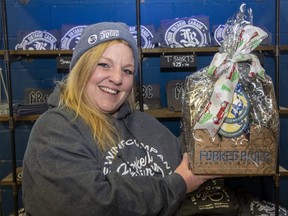 Kellie Budge, tap room manager for Forked River Brewing Company, wears a Forked River hoodie and beanie as she hold a Christmas gift basket with some of the company's beers. Photograph taken on Tuesday, Dec. 6, 2022. Derek Ruttan/The London Free Press