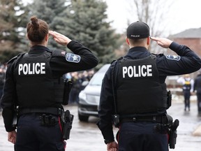 Police officers, along with other first responders, salute as the hearse carrying OPP Const. Grzegorz (Greg) Pierzchala arrives at the Adams Funeral Home in Barrie in December. (Christopher Drost/The Canadian Press)