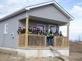 Student builders gather Friday, Dec. 2, 2022, on the porch of a 402-square-foot micro-house they built at Chippewas of the Thames First Nation. (Derek Ruttan/The London Free Press)