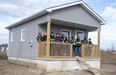 Student builders gather Friday, Dec. 2, 2022, on the porch of a 402-square-foot micro-house they built at Chippewas of the Thames First Nation. (Derek Ruttan/The London Free Press)