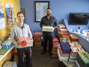 At Allstate Insurance's London North Fanshawe branch, agent Tyler Asselstine, left, and manager Ahmed Elshourfa stack some of the more than 100 boxes of gifts agency employees have put together for the Shoebox Project in London on Tuesday, Dec. 13, 2022. (Derek Ruttan/The London Free Press)