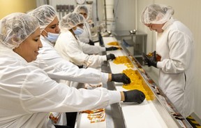 Ivelyses Castelanos and her sister Belvis Vega, both at left, work on a packaging line at Indiva as employees manually pick up the edibles and put them in small packages. Photograph taken on Wednesday, Nov. 30, 2022. (Mike Hensen/The London Free Press)