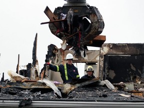 From left, John Milne of the Sarnia fire department and Mike Bird, an investigator with the Ontario Fire Marshal's office, watch on Tuesday, Jan. 17, 2023, as a heavy equipment operator removes burnt sections from Fairwinds Lodge retirement home, which was heavily damaged by a fire overnight Monday. (Terry Bridge/Postmedia Network)