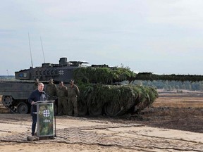 German Chancellor Olaf Scholz speaks next to a Leopard 2 battle tank of the German armed forces Bundeswehr as he visits troops during a training exercise at the military ground in Ostenholz, northern Germany, on Oct. 17, 2022.  Germany on Wednesday approved the delivery of Leopard 2 tanks to Ukraine, after weeks of pressure from Kyiv and many allies. (Photo by Ronny Hartmann / AFP)