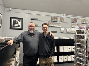 Warren Mitchell, left, and his son Jayden Mitchell stand before some of the empty shelves that displayed their highest value products at CaptCan Comics on Elgin Street in Brantford. Early Monday, a thief targeted the store and made off with more than $75,000 in comic books.