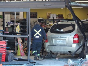 A tow truck driver surveys the damage inside Pistachios Quality Meats and Groceries at 1695 Wonderland Rd. N, where an SUV crashed through the front doors shortly before noon Wednesday. Nobody was injured, police said. (DALE CARRUTHERS/The London Free Press)