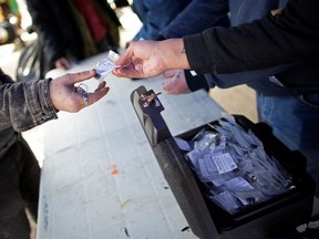 Community members from the Coalition of Peers Dismantling the Drug War hand out clean, tested doses of drugs at a demonstration demanding the legalization and regulation of safe alternatives to the toxic street drug supply in Vancouver, B.C., on April 14, 2022. (Jesse Winter/Reuters)