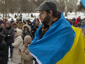 Greg Crossman, whose maternal relatives are Ukrainian, stands wrapped in the country's flag at a vigil outside London city hall to mark the first anniversary of the ongoing Russian invasion. Photo taken on Friday Feb. 24, 2023. Mike Hensen/The London Free Press