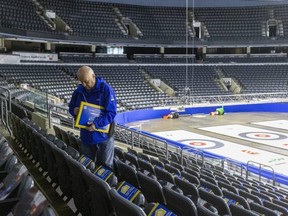 Peter Inch is among the lead organizers of the 2023 Brier. Here, he's placing cardboard signs that can be folded and used as clappers onto the seats at Budweiser Gardens. "I'm just not any good at just standing around," he said. Photograph taken on Tuesday February 28, 2023. (Mike Hensen/The London Free Press)