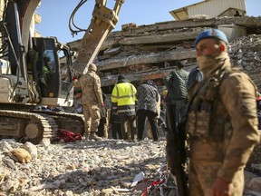Rescue workers stand on a collapsed building in Adiyaman, southern Turkey, Monday, Feb. 13, 2023. The body of a young Canadian woman who was visiting Turkey has been found in the rubble of a building that collapsed during a massive earthquake on Feb. 6.