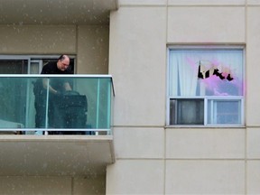 A London police forensic investigator searches for evidence on the balcony of a sixth-floor unit with a shattered window at 621 Kipps Lane on Sunday, March 12, 2023. Two police officers were shot at the building during a standoff with an armed suspect Saturday after police found a dead man inside the building earlier in the day. (Dale Carruthers/The London Free Press