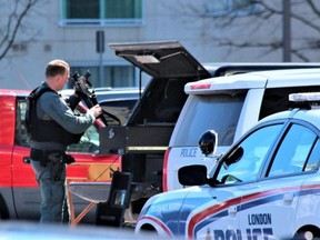 A member of the London police emergency response unit removes a gun from the back of a vehicle before entering 621 Kipps Lane, where an armed man barricaded himself inside an apartment Saturday after a man was found dead earlier. (Dale Carruthers/The London Free Press)